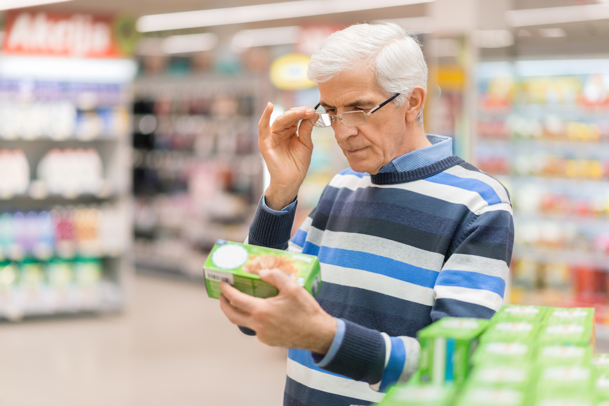 Man in a grocery store looking at a food label